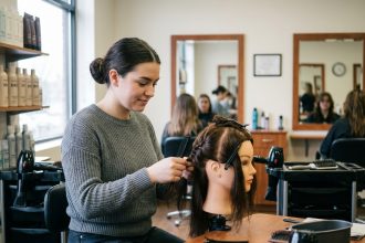 Jeune femme en coiffure pratique sur un mannequin dans une &eacute;cole de beaut&eacute;